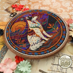 Peut inclure: Une broderie au point de croix circulaire dans un cerceau en bois, repr&eacute;sentant un loup stylis&eacute; sur un fond color&eacute;. Le loup est blanc avec des marques noires et est entour&eacute; d'une vari&eacute;t&eacute; de couleurs, notamment l'orange, le violet, le bleu et le vert. La broderie est encadr&eacute;e par un cerceau en bois brun.