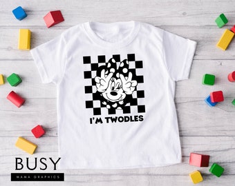 May include: White t-shirt with a black and white checkered background and a black and white image of a cartoon mouse with the text "I'm Twodles" printed on the front.