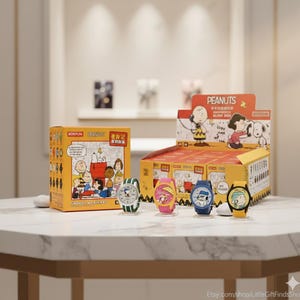 May include: A display of colorful Peanuts-themed watches. The watches feature Snoopy, Charlie Brown, and other characters. The watches are on display with a yellow box featuring Peanuts characters and text. The watches have different colored bands.