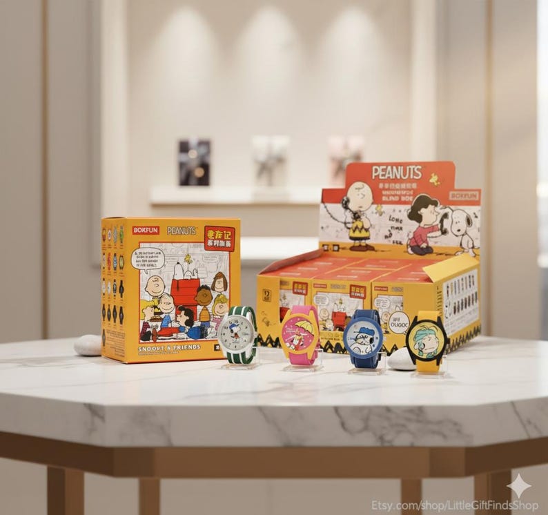 May include: A display of colorful Peanuts-themed watches. The watches feature Snoopy, Charlie Brown, and other characters. The watches are on display with a yellow box featuring Peanuts characters and text. The watches have different colored bands.