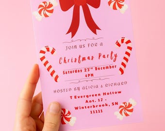 Pode incluir: Um cartão de convite retangular rosa claro com um grande laço vermelho no topo, duas bengalas doces e quatro doces embrulhados. O texto diz: Join us for a Christmas Party, Saturday 23rd December 4 PM, Hosted by Alicia & Richard, 1 Evergreen Holtow, Apt. 12, Winterbrook, SN 11111.