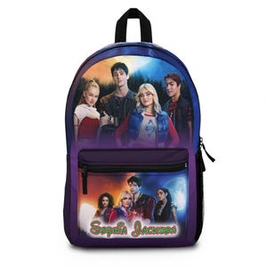 May include: Purple backpack featuring a group of people with a night sky background. The backpack has a front pocket and a black handle. The name "Sophia Jackson" is written in green script at the bottom.