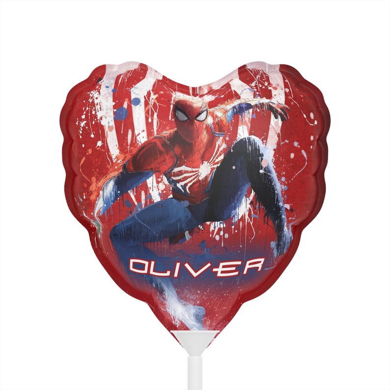 May include: A heart-shaped balloon featuring Spider-Man in a dynamic pose against a red background with white and blue paint splatters. The name "OLIVER" is printed in white. The balloon is attached to a white stick.