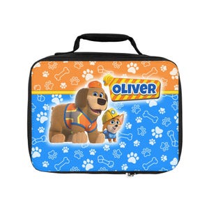 May include: A rectangular lunch bag with a black handle and zipper. The bag features a cartoon design with two dogs, paw prints, and the name "OLIVER". The background is blue and orange.
