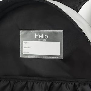 May include: Black backpack interior with a clear label that reads "Hello I belong to" above blank fields for name, address, and phone. The backpack has a black and white striped design on the exterior.