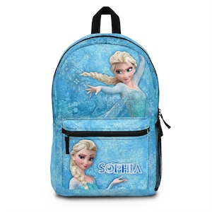 May include: A blue backpack featuring Elsa from Frozen. The backpack has a front zippered pocket and a side mesh pocket. The name "Sophia" is printed on the front. The background has a snowflake design.