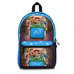 May include: A blue backpack featuring a cloud pattern and a graphic of Toy Story characters. The main compartment and front pocket display a green frog-shaped frame with the text Hi! Let's play! and the name Oliver printed on the front.