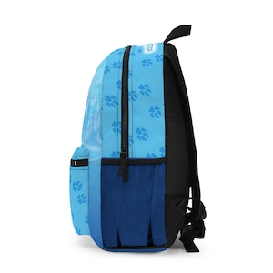 May include: A blue backpack with a paw print pattern. The backpack has a black back and straps, a front pocket, and a side mesh pocket. The zipper is black.