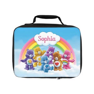 May include: A black lunch bag featuring a colorful design with cartoon bears, a rainbow, and the name "Sophia" in a cloud. The bears are in various colors, with a blue sky background.
