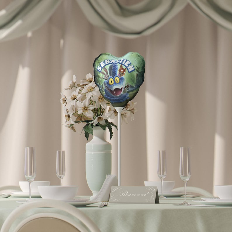 以下が含まれることがあります： セバスチャンという名前と漫画のキャラクターが描かれたハート型の風船。風船は緑と青で、笑顔のキャラクターがいます。テーブルセッティングには花、グラス、そして「予約済み」のサインが含まれており、お祝いに最適です。