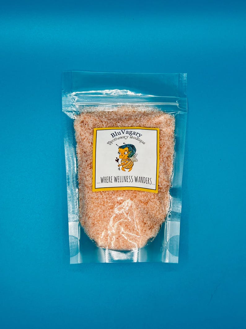 May include: A clear plastic bag filled with pink Himalayan salt. The bag has a label that reads "Blu Vagary Apothecary Boutique...Where Wellness Wanders."
