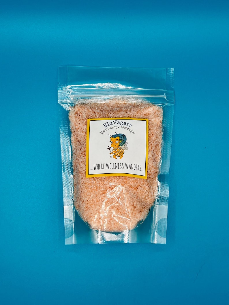 May include: A clear plastic bag filled with pink Himalayan salt. The bag has a label that reads "Blu Vagary Apothecary Boutique...Where Wellness Wanders."