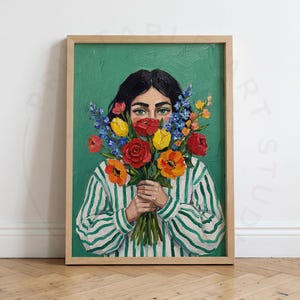 Pode incluir: Uma pintura a óleo em tela emoldurada retratando uma pessoa de cabelos escuros vestindo uma camisa branca com listras verdes verticais. A pessoa segura um buquê vibrante de flores vermelhas, amarelas, laranjas e azuis frente ao rosto.