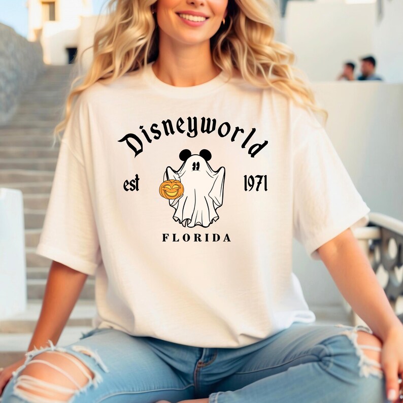 Puede incluir: Camiseta blanca con un gr&aacute;fico negro de un fantasma sosteniendo una calabaza. El texto "Disneyworld est 1971 FLORIDA" est&aacute; impreso en la camiseta.