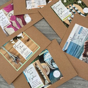 May include: A selection of craft tutorial cards for macrame projects. The cards display projects like a pineapple, heart keychain, daisy keychain, plant holder, twist keychain, and sea turtle. The cards are on a brown background with the text "Giftable Tutorials".