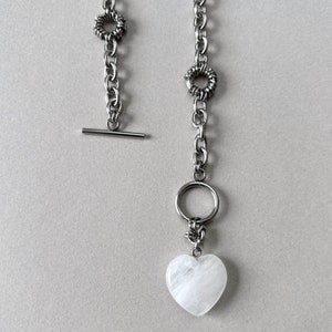 The statement necklace features a clear quartz pendant and toggle clasp.