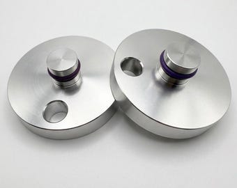 May include: Two circular silver metal discs, each featuring a central raised cylindrical post with a purple rubber O-ring and a single circular hole positioned near the outer edge of the disc, presented on a plain white background.