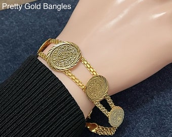 May include: Gold coin bracelet with multiple round coins connected by a chain. The bracelet is on a person's wrist. The text "Coin Bracelet" is visible below the bracelet.