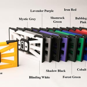 May include: A collection of multi-colored game console accessories. The image displays a yellow accessory with a black logo, and a row of accessories in colors like white, gray, purple, green, red, and orange.