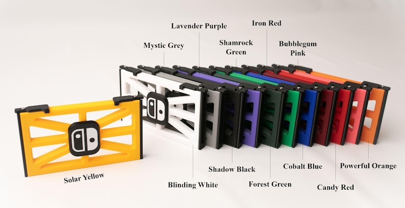 May include: A collection of multi-colored game console accessories. The image displays a yellow accessory with a black logo, and a row of accessories in colors like white, gray, purple, green, red, and orange.