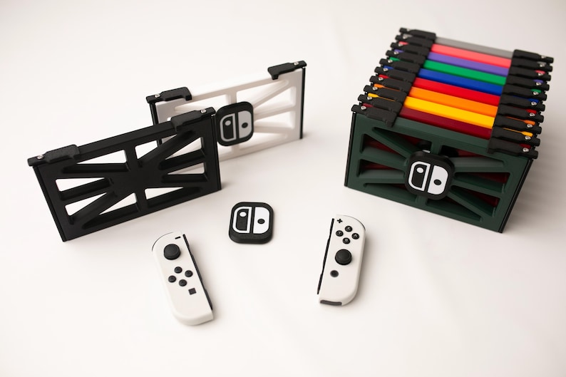 May include: A collection of Nintendo Switch accessories, including a black and white console dock, controller, and a green storage case with colorful game cartridges. The accessories are arranged on a white surface.
