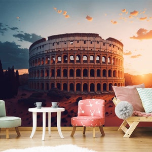 Può includere: Un'illustrazione colorata del Colosseo a Roma, Italia, con un cielo al tramonto sullo sfondo. L'immagine è utilizzata come murale in una stanza con mobili, tra cui una poltrona rosa, una poltrona verde chiaro e un divano in legno con cuscini.