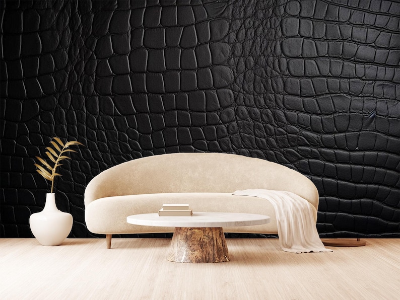 May include: A modern living room scene featuring a cream-colored sofa, a round coffee table with a wood base, and a black textured wall. A white vase with a gold-colored plant and a cream-colored throw blanket add to the decor.