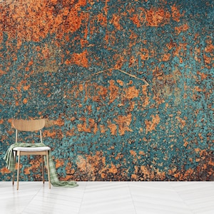 May include: A teal and orange textured wall with a wooden chair and a green throw blanket in front of it.