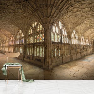 May include: A high-ceilinged, arched hallway with stained glass windows and a stone floor. The hallway is empty except for a wooden chair in the foreground.