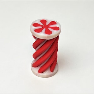 以下が含まれることがあります： 赤と白のらせん模様の3Dプリント装飾オブジェクト。上部と下部は白で、赤い花のような模様があります。オブジェクトは円筒形で、白い背景に立っています。