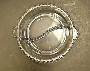 Puede incluir: Un plato de servir dividido de vidrio transparente con un borde de cuentas. El plato tiene dos secciones separadas por un divisor curvo.