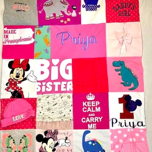 May include: A memory quilt constructed from various infant clothing items, featuring patches with Minnie Mouse, dinosaurs, an elephant, and text including "Big Sister," "Priya," "Daddy's Girl," and "Keep Calm and Carry Me" in pink, white, and grey.