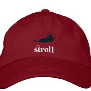 May include: A red baseball cap with a green island silhouette and the word "stroll" embroidered in white.