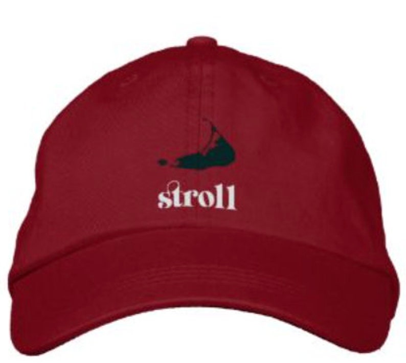 May include: A red baseball cap with a green island silhouette and the word "stroll" embroidered in white.