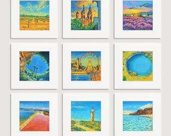 May include: Nine framed landscape paintings with white mats. The artworks depict various scenes, including a vineyard, a cathedral, a lavender field, a coastal view, a Ferris wheel, a lake, a salt flat, a lighthouse, and a beach.