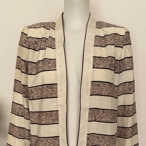 May include: A white and brown striped open-front jacket with a black trim. The jacket has a marbled pattern on the brown stripes.