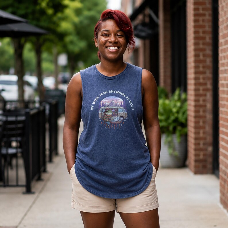 Woman wearing blue tank top with graphic of frog and van, "We Work From Anywhere At Dawn".