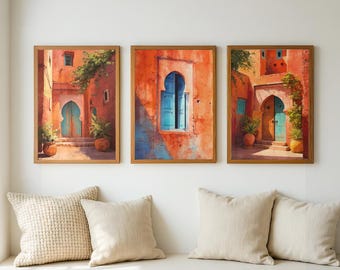 May include: Three framed art prints depicting Moroccan architecture. The artwork features vibrant orange walls, turquoise doors and windows, and lush greenery. The prints are displayed above a cream-colored bench with pillows.