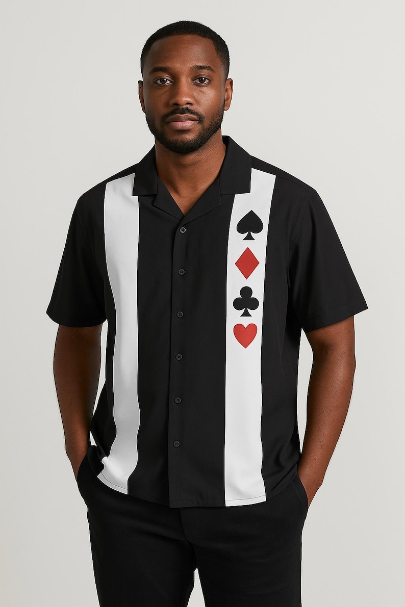 May include: Black button-down shirt with a white vertical stripe down the center and playing card suit symbols. The shirt has short sleeves and a classic collar. The suits are spade, diamond, club, and heart.