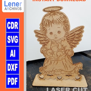 Puede incluir: Figurita de ángel de madera cortada con láser que sostiene una cesta de pollitos. El ángel tiene un halo y alas. La base de la figurita tiene un diseño de corazón.