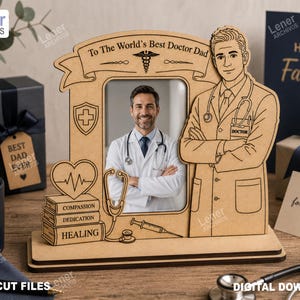 Puede incluir: Un marco de fotos de madera cortado con láser que presenta una ilustración de un médico, un estetoscopio, una jeringa y una pila de libros etiquetados como Compassion, Dedication y Healing. La pancarta superior dice To The World's Best Doctor Dad.