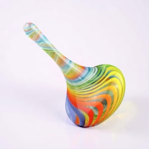 May include: A colorful, hand-blown glass art piece with a heart-shaped base and a long, curved neck. The glass features swirling bands of red, orange, yellow, green, and blue. The piece is set against a white background.