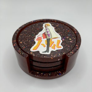 May include: Set of four brown coasters with a glittery finish. The top coaster features a printed image of a character from the anime "Howl's Moving Castle".