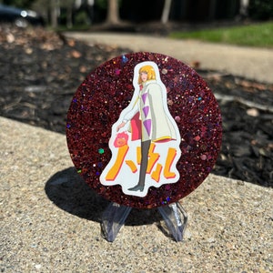 May include: A red glitter round coaster featuring a white anime character wearing a white coat with purple accents and a red and yellow Japanese character in the background.
