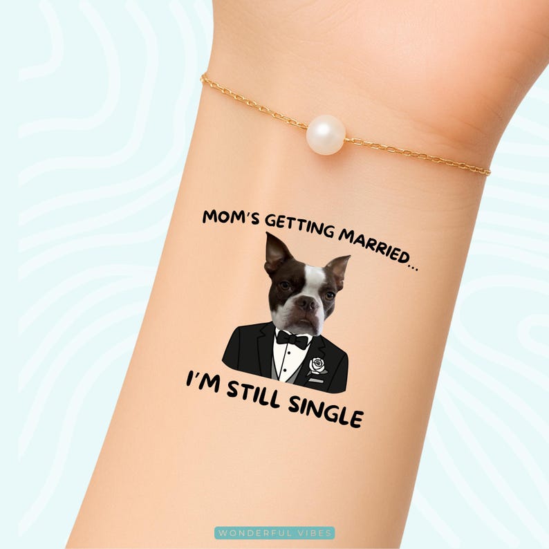 Peut inclure: Tatouage temporaire repr&eacute;sentant un Boston Terrier en smoking avec le texte "Mom's Getting Married... I'm Still Single." Le motif est sur une peau claire, avec un bracelet dor&eacute; et une perle.
