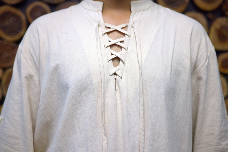 May include: A white linen shirt with a lace-up neckline. The shirt has a relaxed fit and long sleeves.