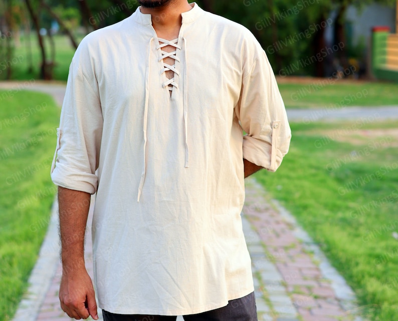 May include: A cream-colored, long-sleeved shirt with a lace-up neckline. The shirt is made of a lightweight fabric and has a relaxed fit.