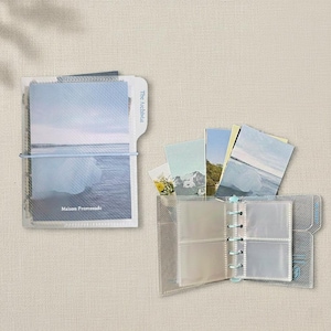 May include: Clear plastic photo album with a light blue spiral binding. The album is open, revealing several photo sleeves and a few landscape photos. The text "The Archivist" and "Maison Promenade" are visible.