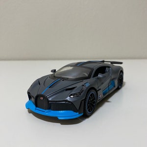Op de afbeelding: Een grijs en blauw speelgoedautomodel van een Bugatti Chiron.