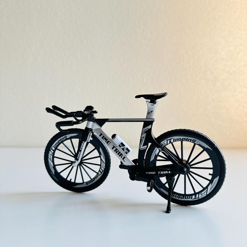 May include: A black and white time trial bicycle with a white water bottle holder and the words "Time Trial" printed on the frame.